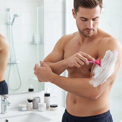 Homme se rase les bras avec rasoir de sureté 